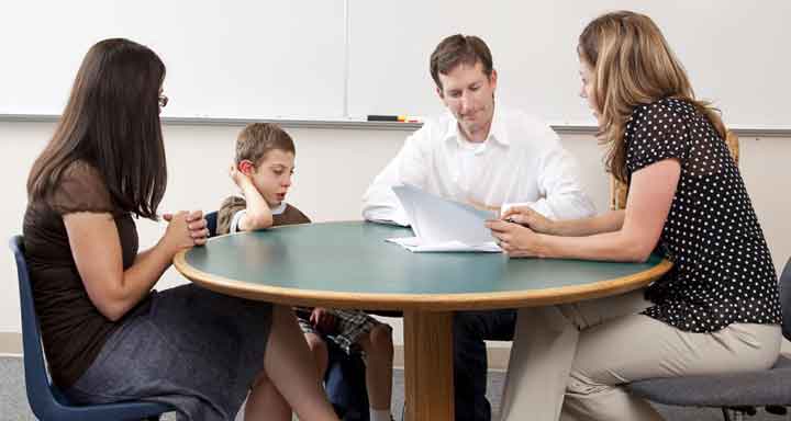 teacher sitting at table with parents and child