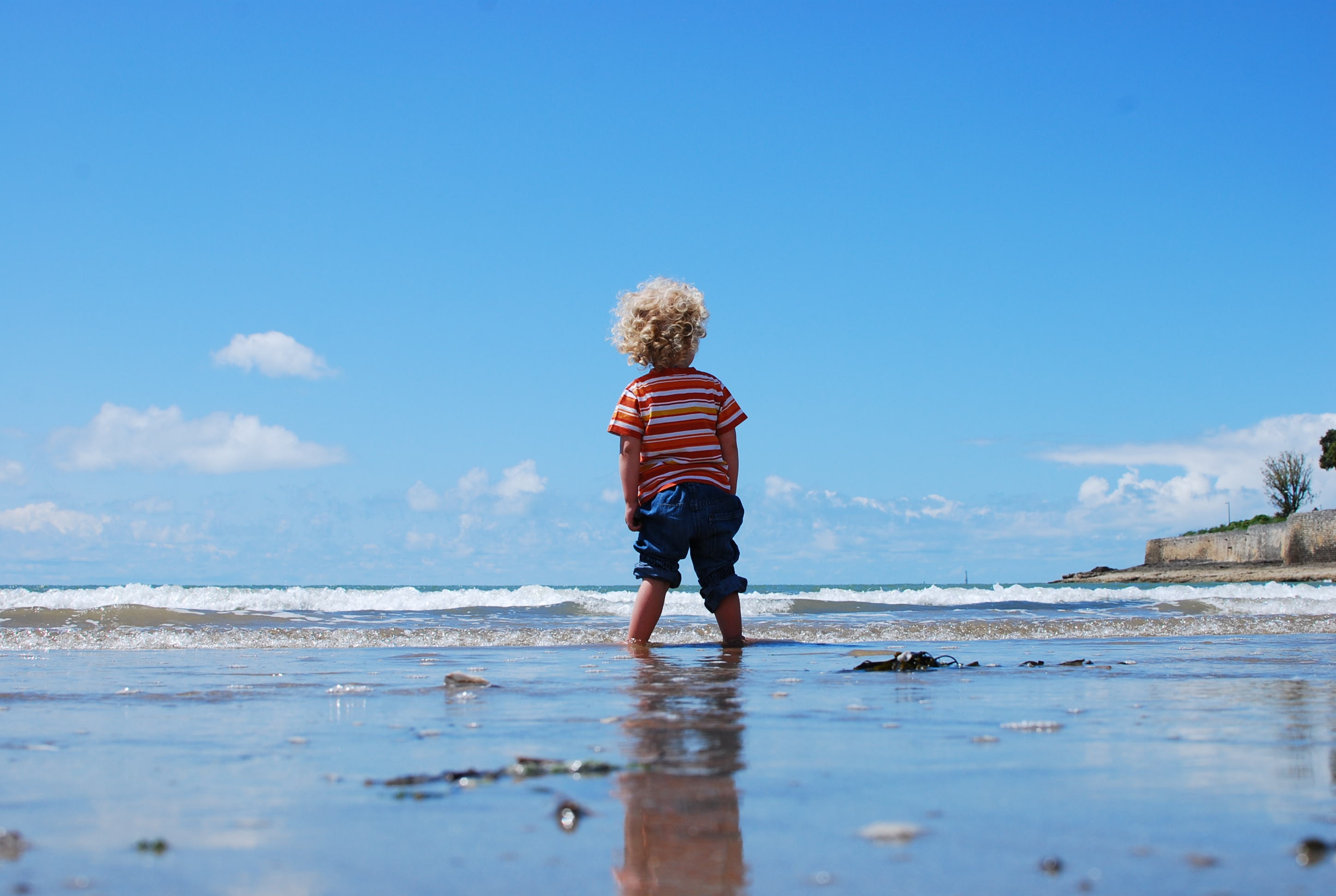 young child standing at edge of beach